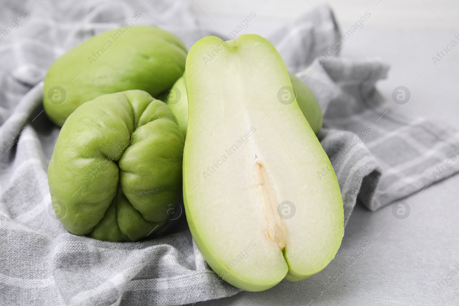 Photo of Cut and whole chayote on gray table, closeup