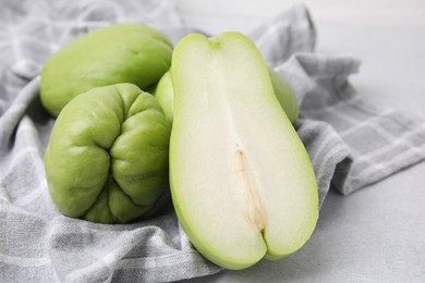 Cut and whole chayote on gray table, closeup