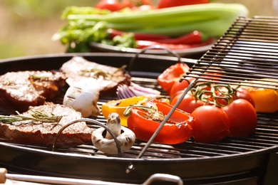 Photo of Modern grill with meat and vegetables outdoors, closeup