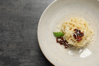 Tasty spaghetti with sun-dried tomatoes and parmesan cheese on grey table, top view and space for text. Exquisite presentation of pasta dish