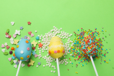 Egg shaped cake pops for Easter celebration on green background, flat lay