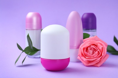 Photo of Composition with different female roll-on deodorants on purple background