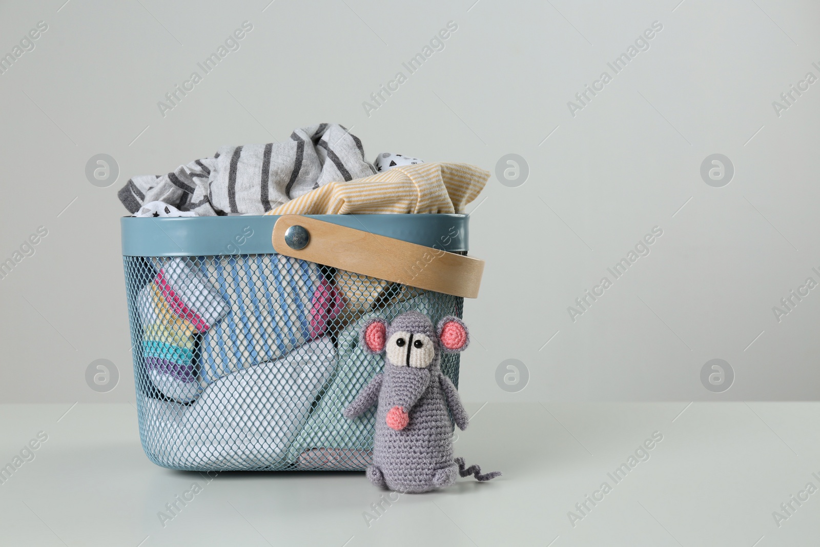 Photo of Laundry basket with different children's clothes and toy on light background. Space for text