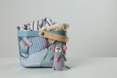 Laundry basket with different children's clothes and toy on light background. Space for text