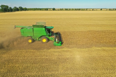 Photo of Modern combine harvester working in field on sunny day. Agriculture industry
