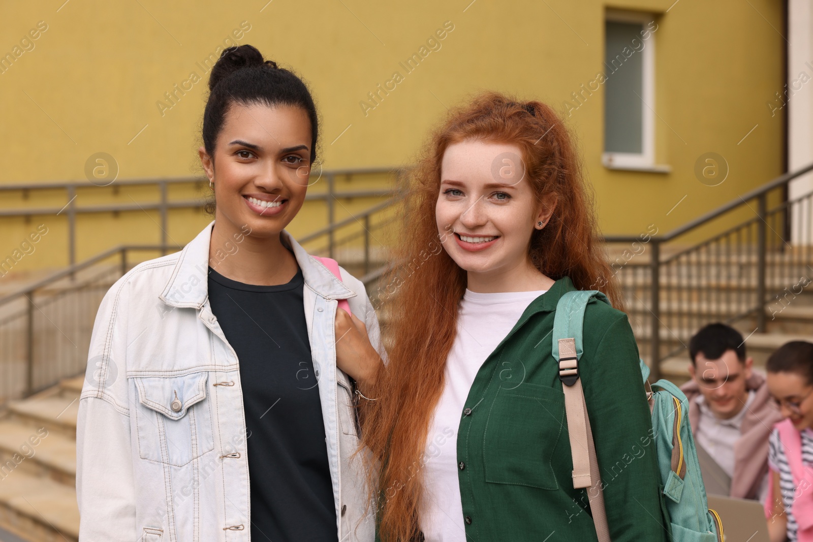 Photo of Portrait of happy young students with backpacks outdoors