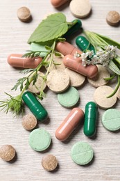 Photo of Different pills and herbs on wooden table, above view. Dietary supplements