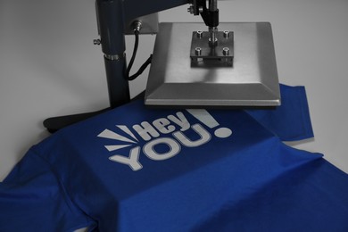 Printing logo. Heat press with t-shirt on white table, closeup