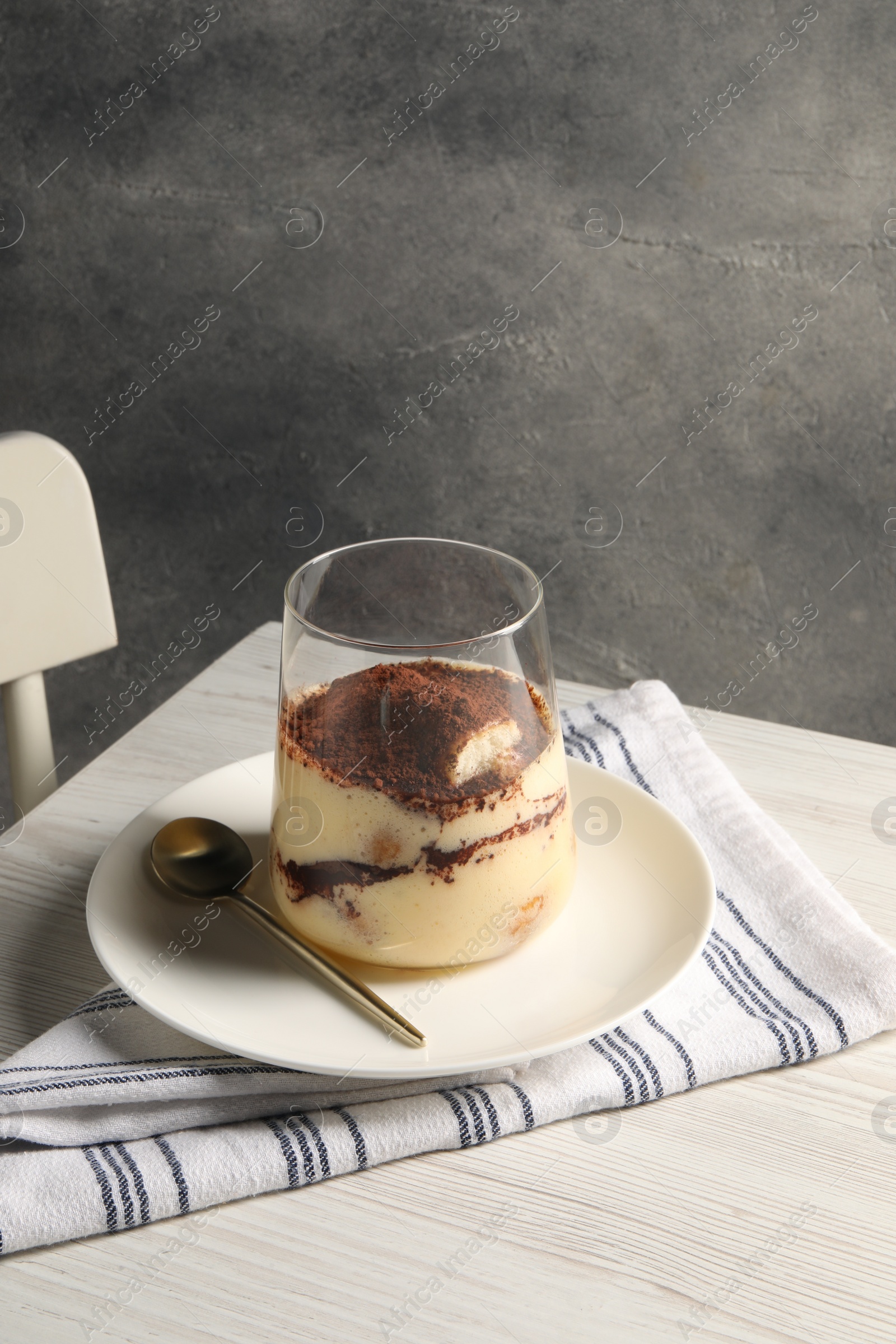 Photo of Delicious tiramisu in glass on white wooden table