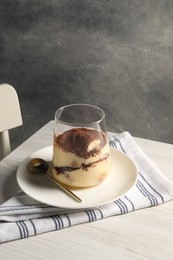 Photo of Delicious tiramisu in glass on white wooden table