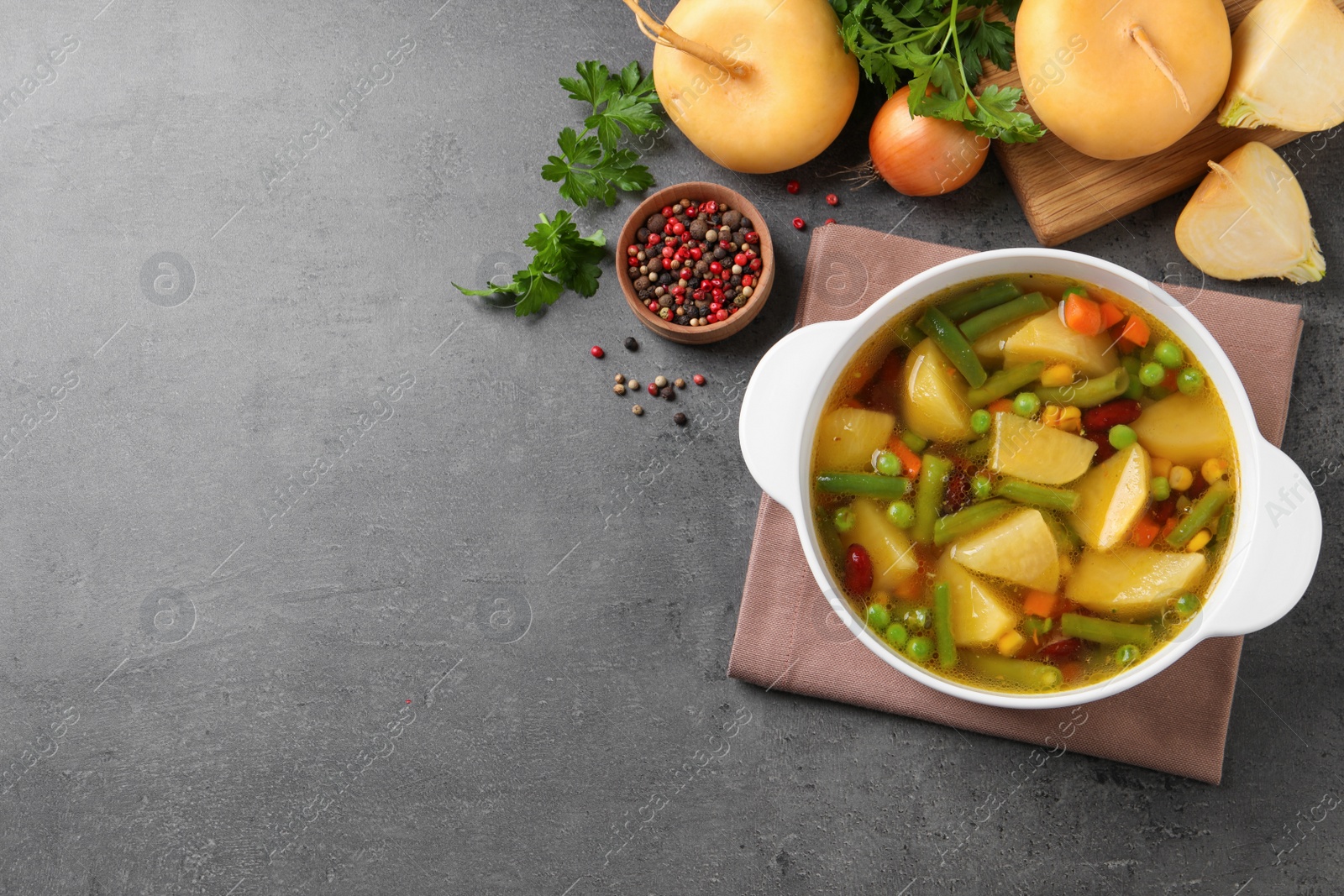 Photo of Bowl of delicious turnip soup on grey table, flat lay. Space for text