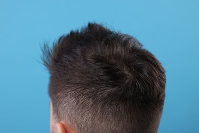 Man with healthy hair on light blue background, closeup