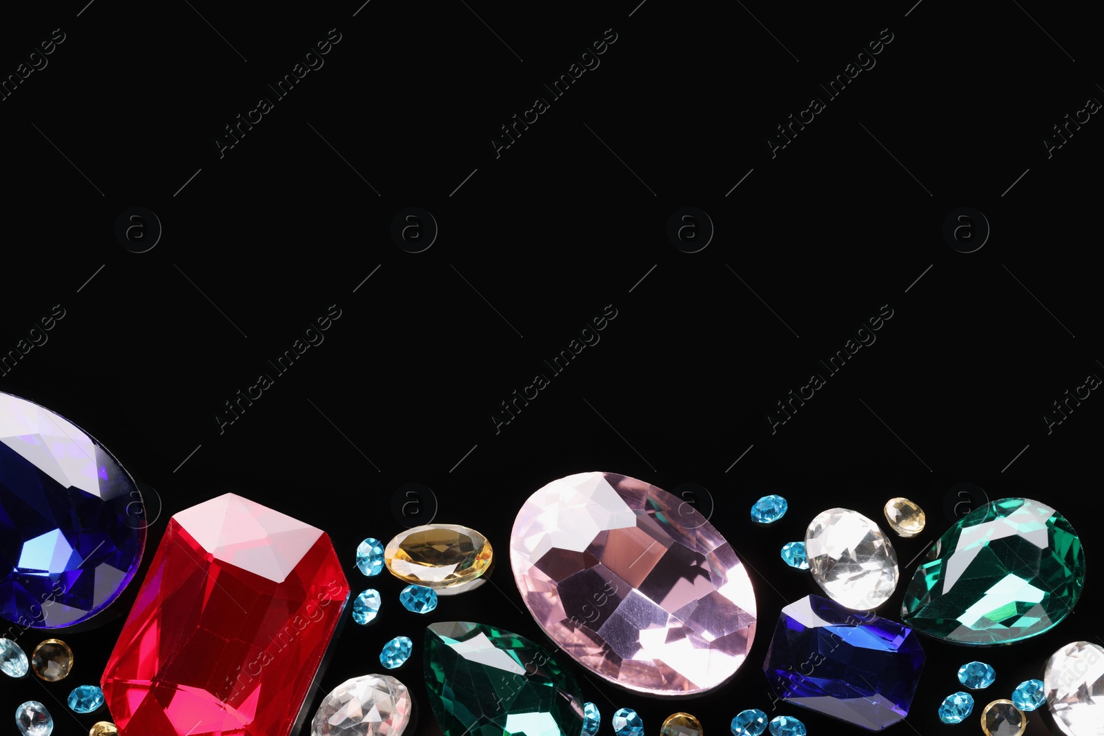 Photo of Different beautiful gemstones for jewelry on black background, flat lay. Space for text