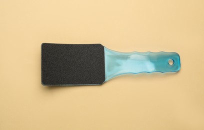 Photo of Light blue foot file on beige background, top view. Pedicure tool