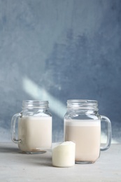 Photo of Mason jars with protein shake and scoop of powder on table. Space for text