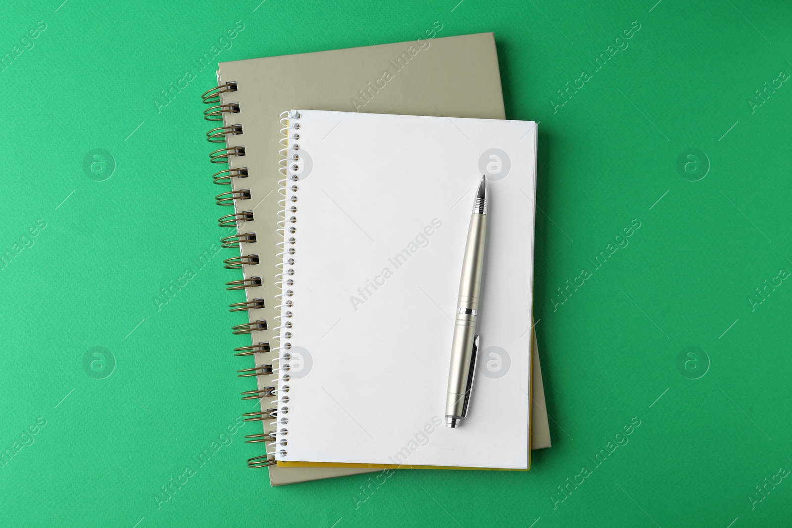 Photo of Notebooks and pen on green background, top view