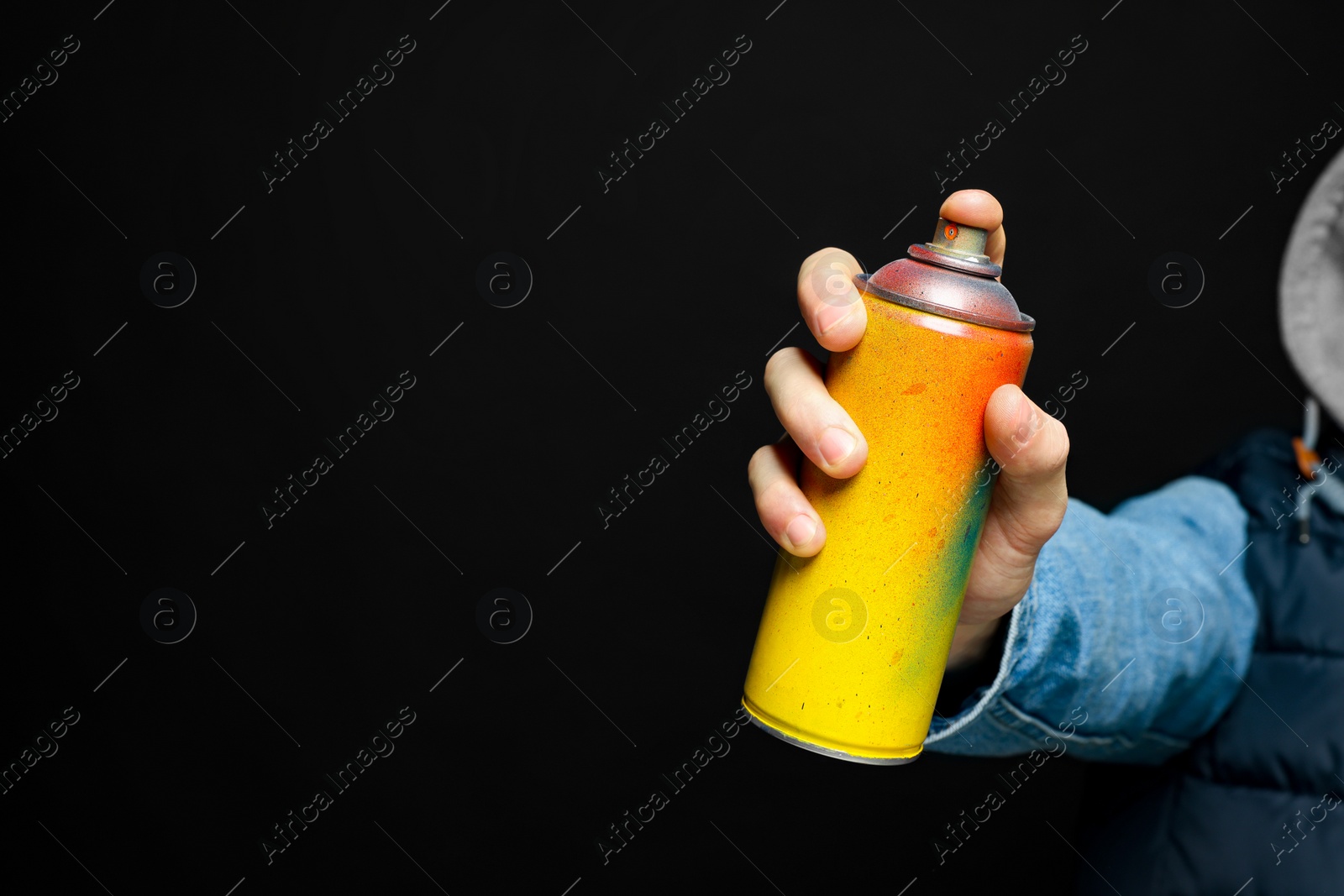 Photo of Man holding used can of spray paint on black background, closeup. Space for text