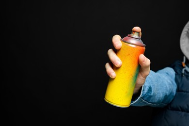 Man holding used can of spray paint on black background, closeup. Space for text