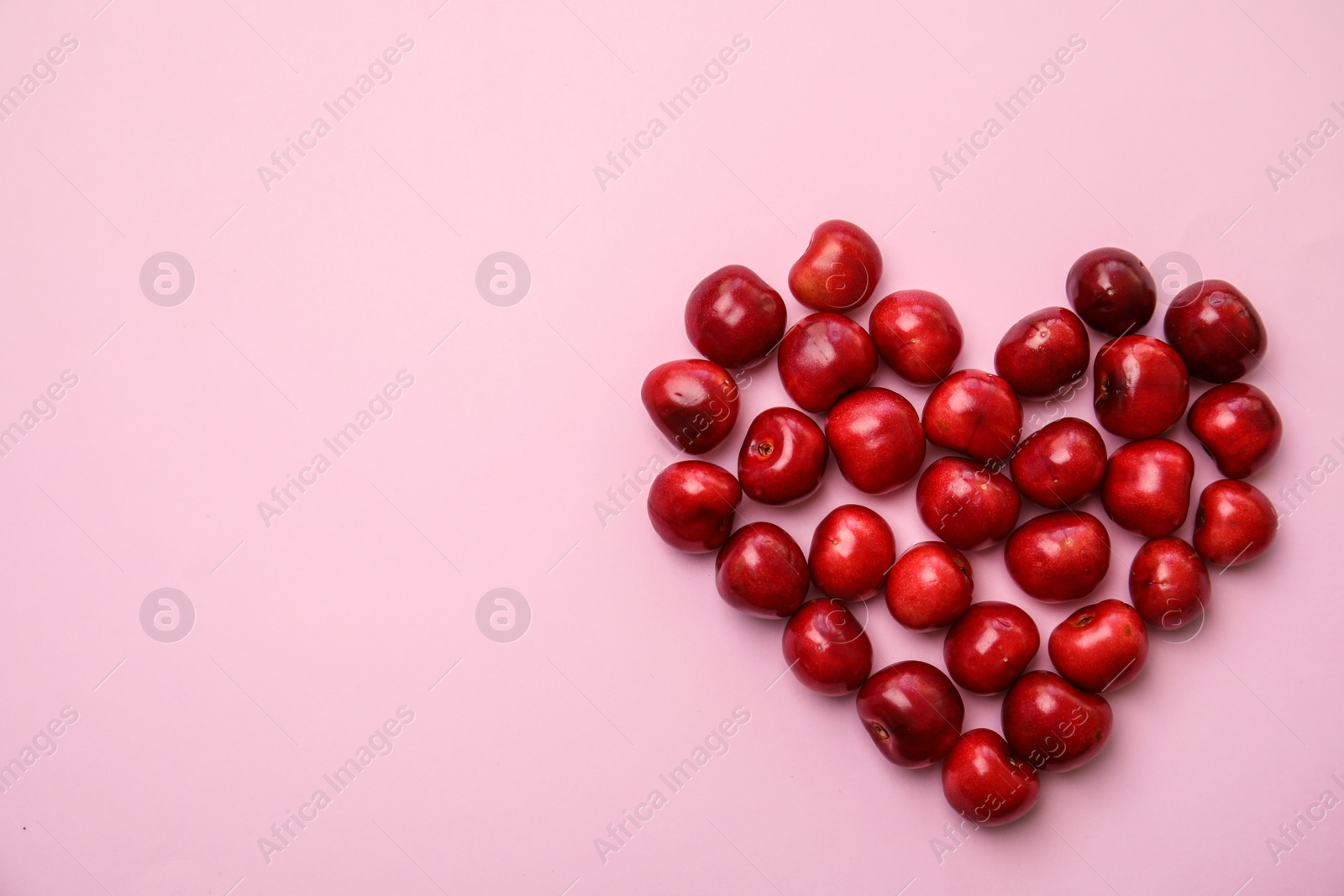 Photo of Heart made of sweet red cherries on color background