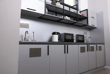 Photo of Hostel kitchen interior with modern furniture and appliances