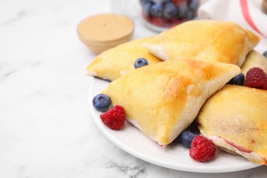 Delicious samosas with berries on white marble table, closeup. Space for text