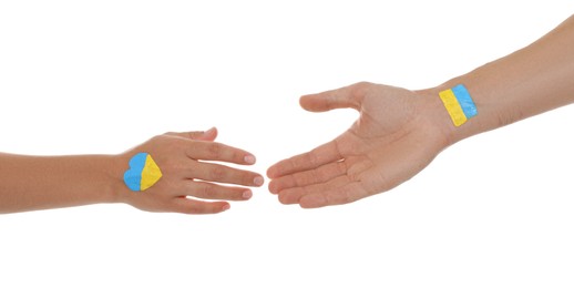 Photo of Man and woman with painted Ukrainian flags on their hands against white background, closeup