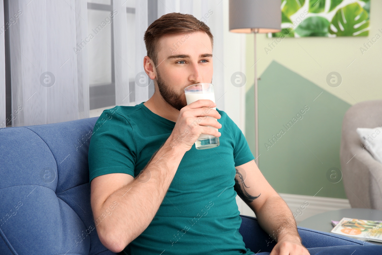 Photo of Young man drinking tasty milk at home