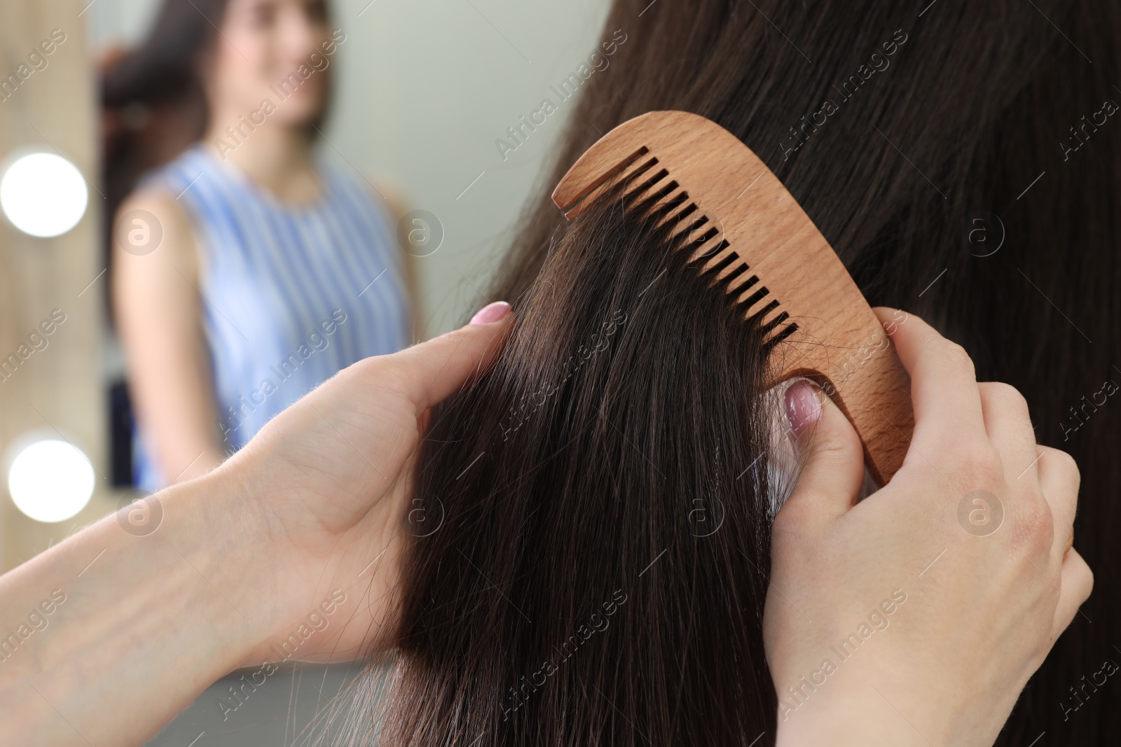 Photo of Woman combing friend's hair indoors, closeup view