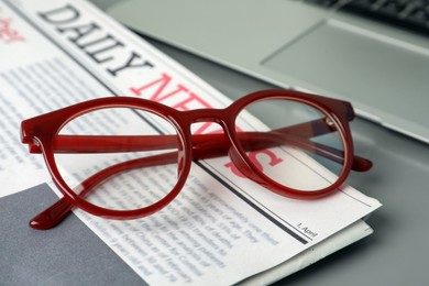 Photo of Newspaper, laptop and glasses on grey table, closeup