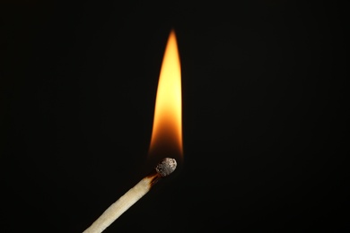 Photo of Burning matchstick on black background, closeup. Space for text