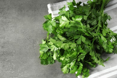 Photo of Bunch of fresh green parsley leaves on grey table, closeup. Space for text