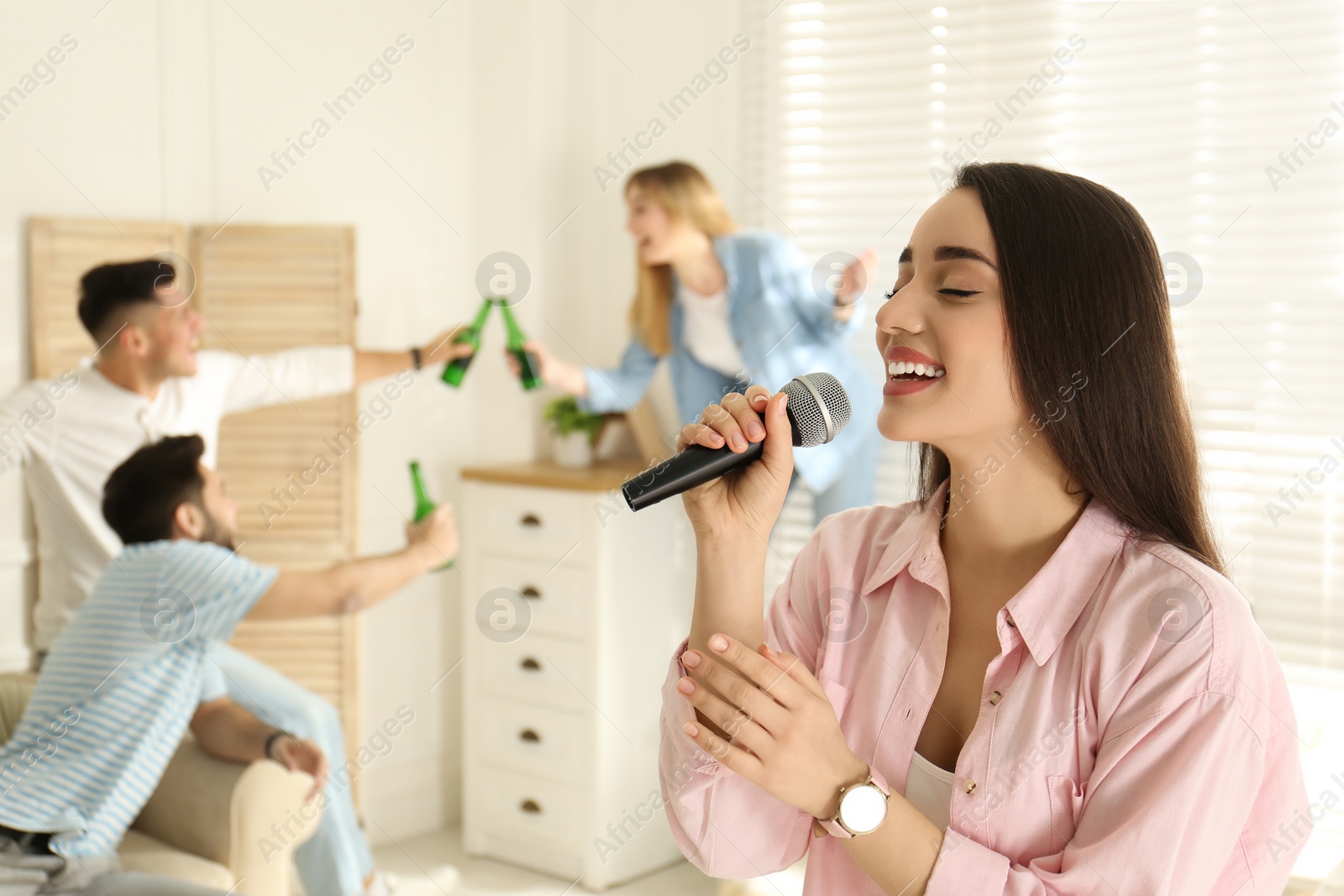 Photo of Young woman singing karaoke with friends at home