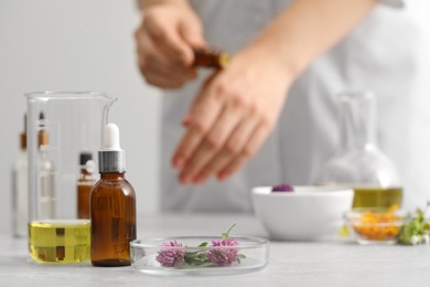 Bottle of cosmetic oil and ingredients on light grey table, selective focus. Space for text