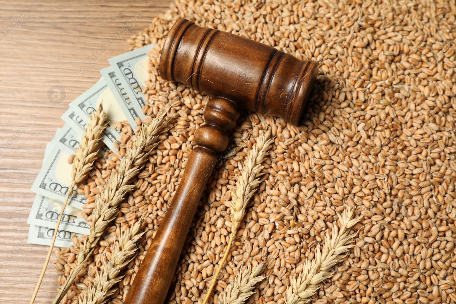 Photo of Dollar banknotes, judge's gavel, wheat ears and grains on wooden table, flat lay. Agricultural business