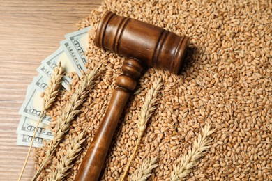 Dollar banknotes, judge's gavel, wheat ears and grains on wooden table, flat lay. Agricultural business