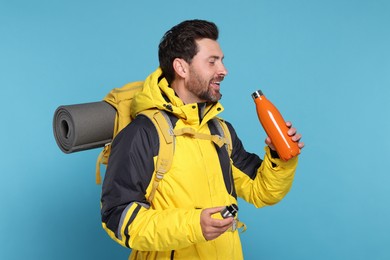 Photo of Man with backpack and thermo bottle on light blue background. Active tourism