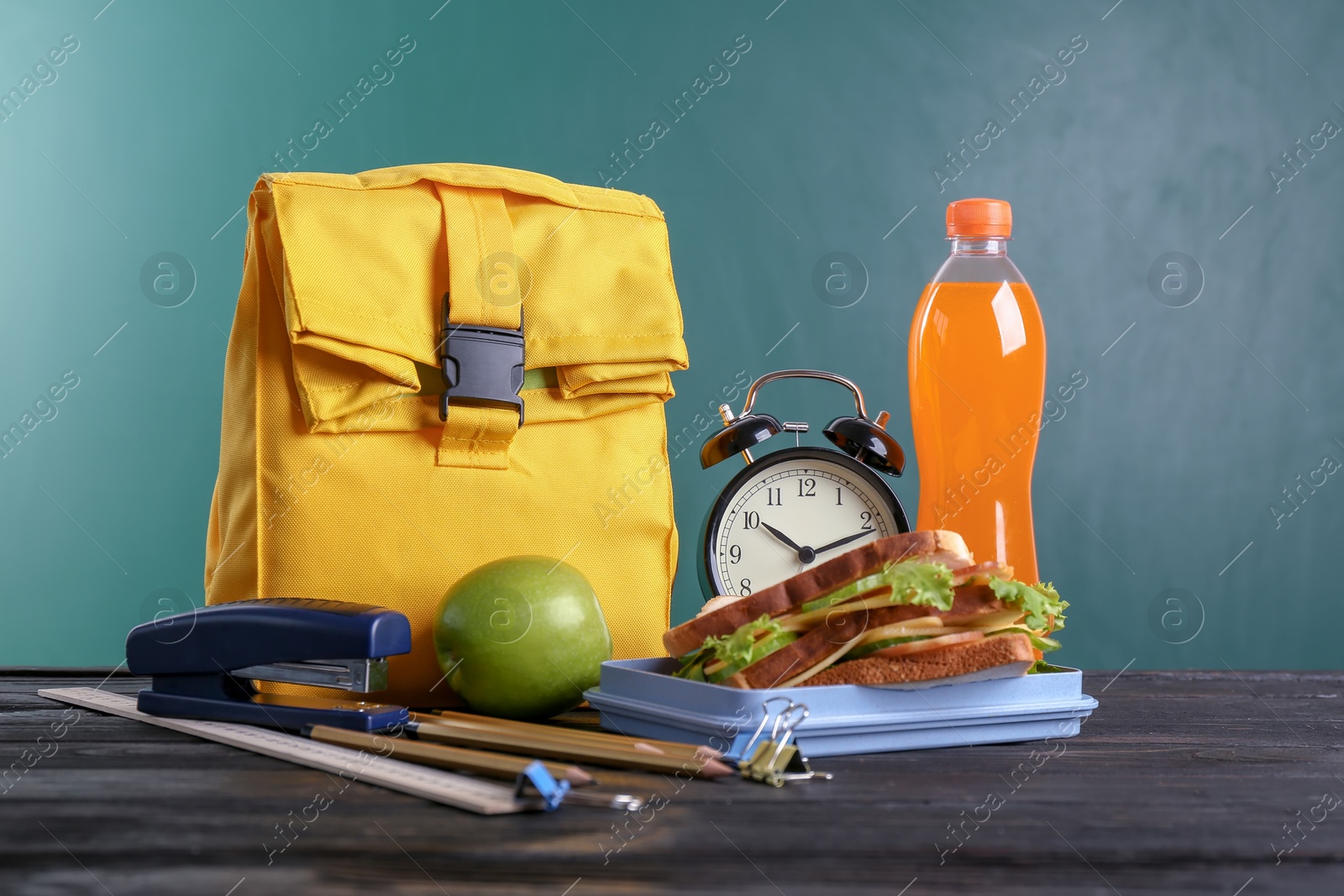 Photo of Composition with lunch box and food on table against blackboard