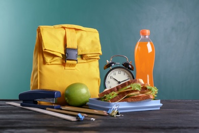 Photo of Composition with lunch box and food on table against blackboard