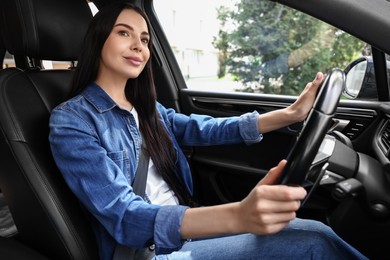 Woman with seatbelt holding steering wheel while driving her car