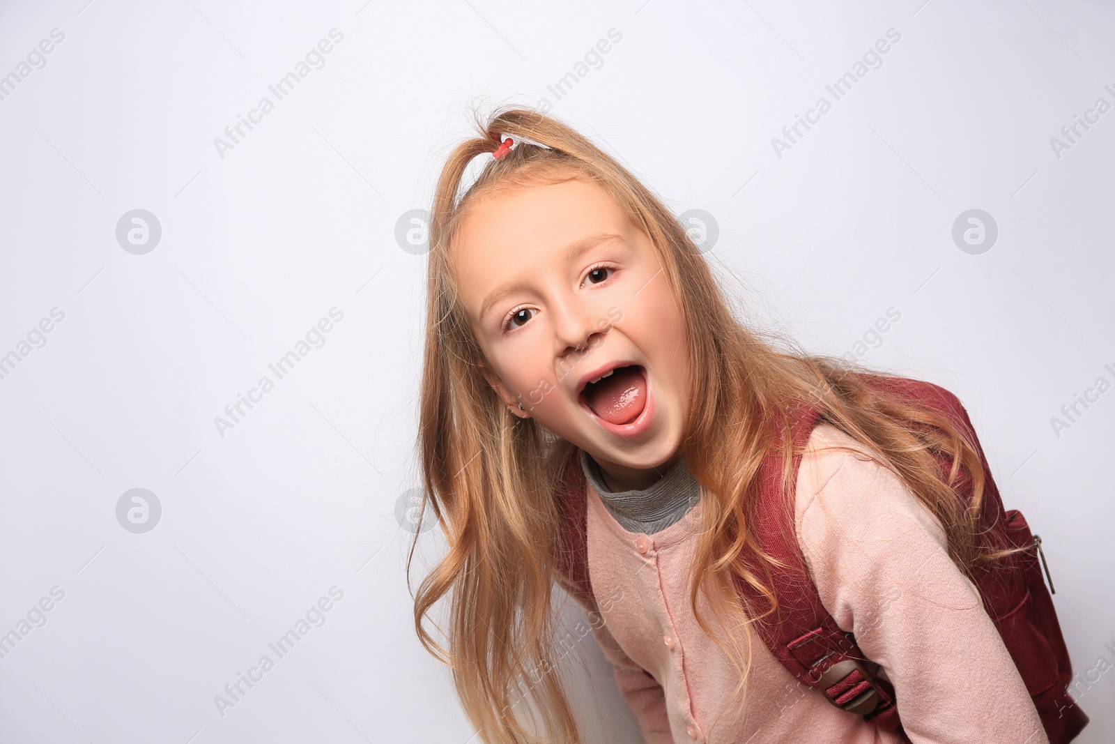 Photo of Emotional little girl with backpack on white background. Space for text