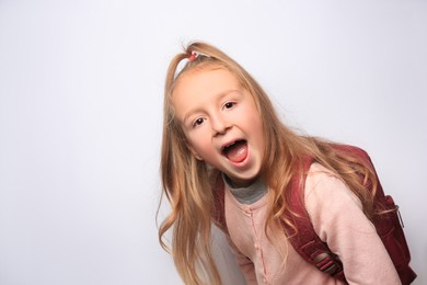 Emotional little girl with backpack on white background. Space for text