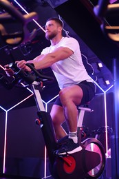 Photo of Young man training on exercise bike in fitness club