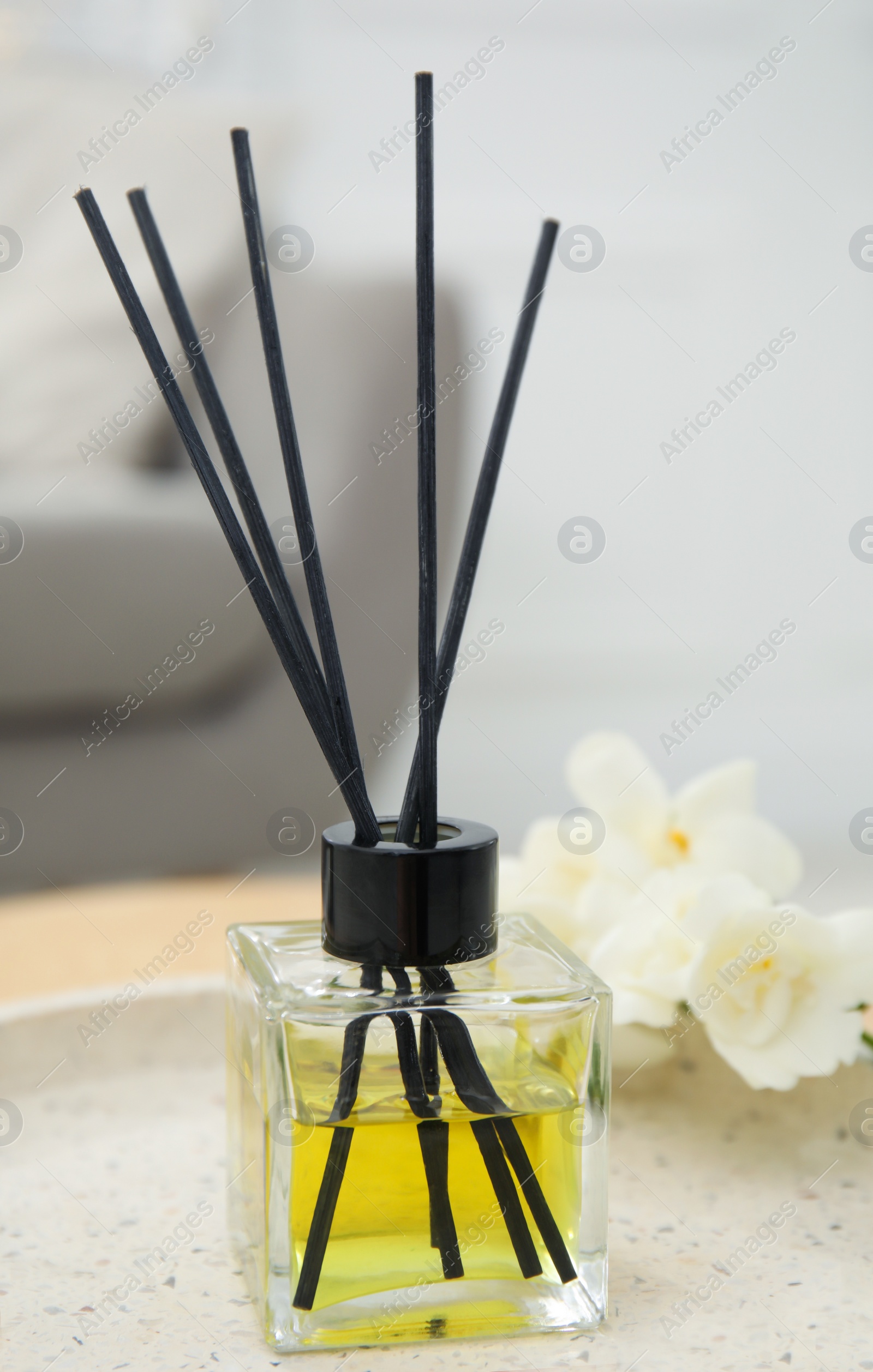 Photo of Reed diffuser with freesia on table in living room, closeup