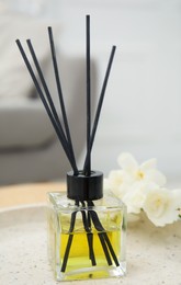 Reed diffuser with freesia on table in living room, closeup