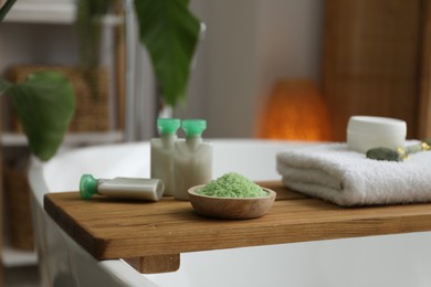 Photo of Wooden tray with spa products on bath tub in bathroom