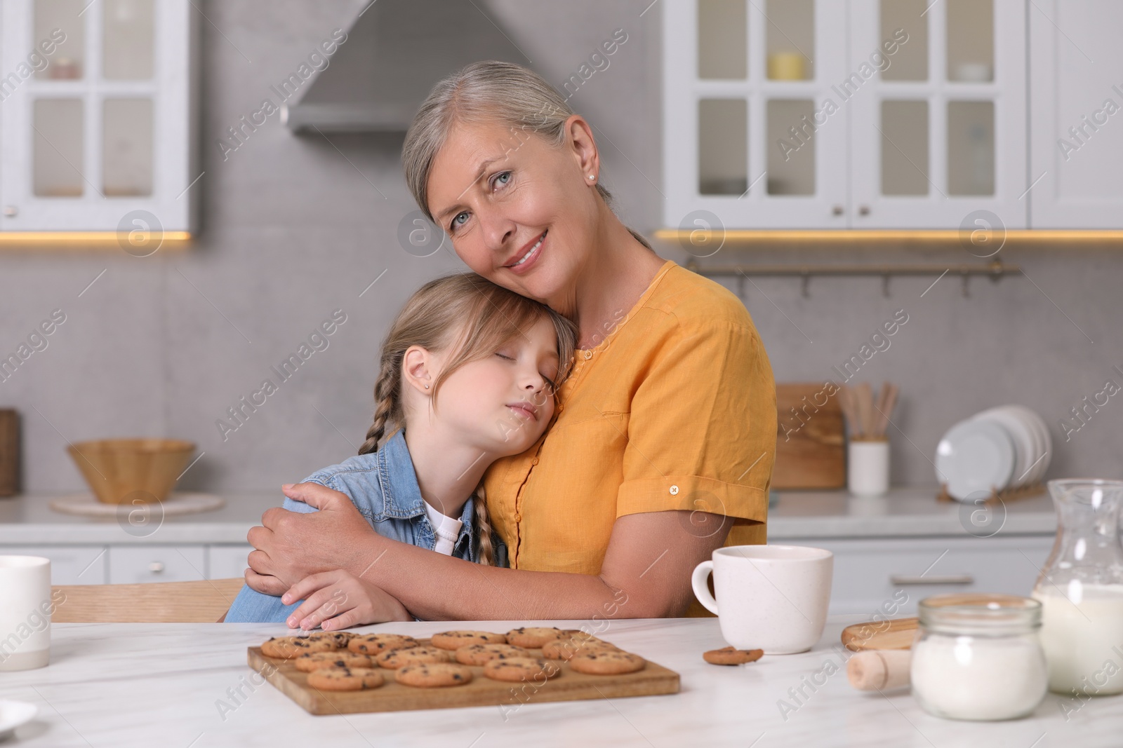 Photo of Happy grandmother hugging her granddaughter in kitchen