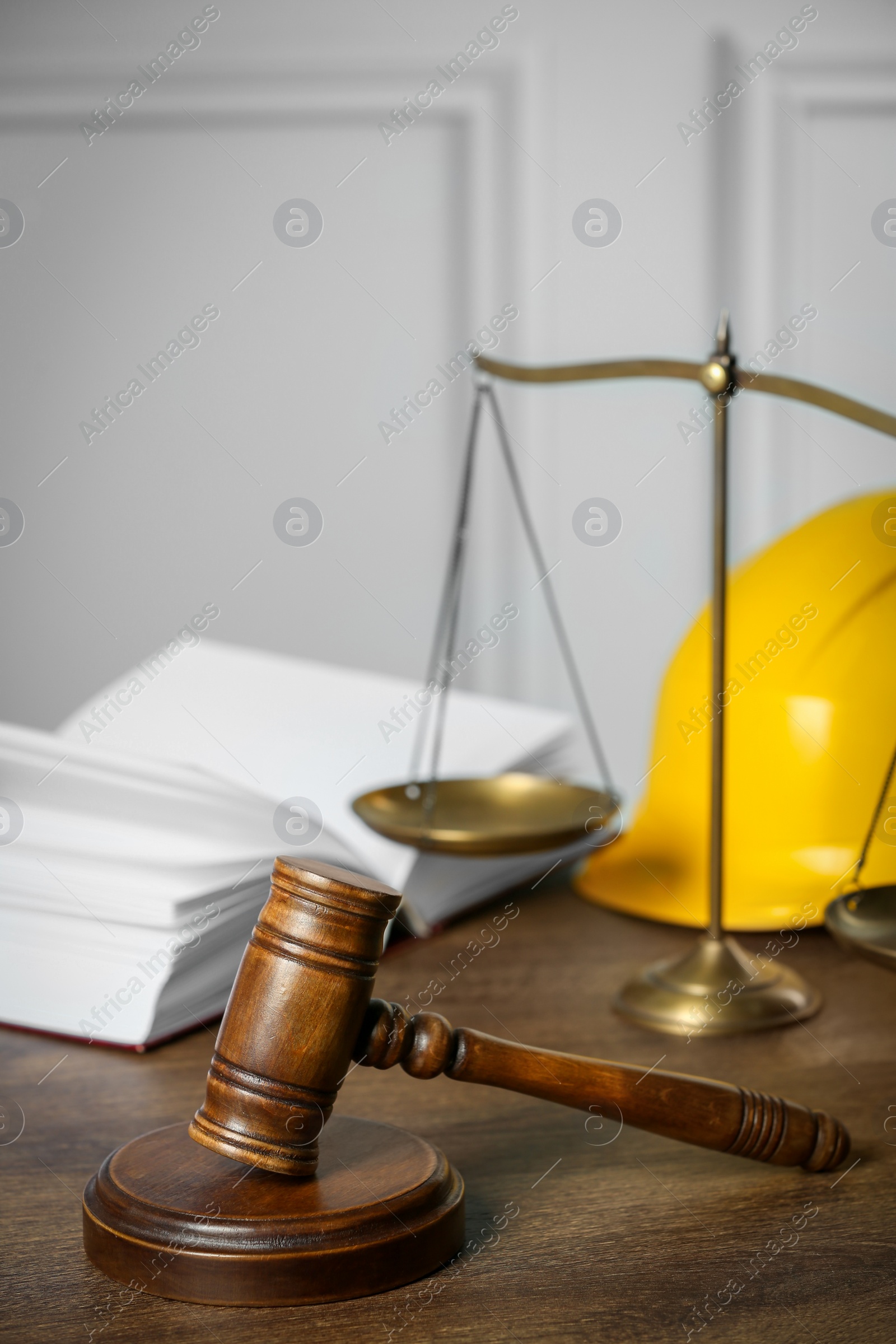Photo of Labour, construction and land law concepts. Judge gavel, scales of justice, open book with hardhat on wooden table