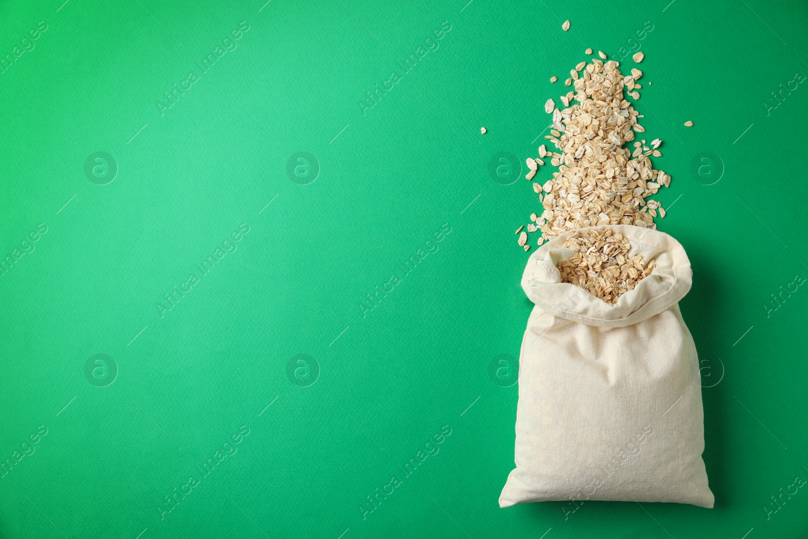 Photo of Cotton eco bag with oat flakes on green background , top view. Space for text