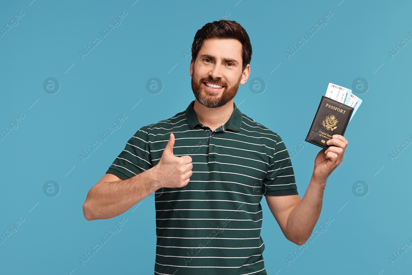 Photo of Smiling man with passport and tickets showing thumb up on light blue background