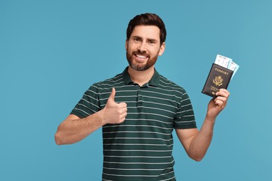 Photo of Smiling man with passport and tickets showing thumb up on light blue background